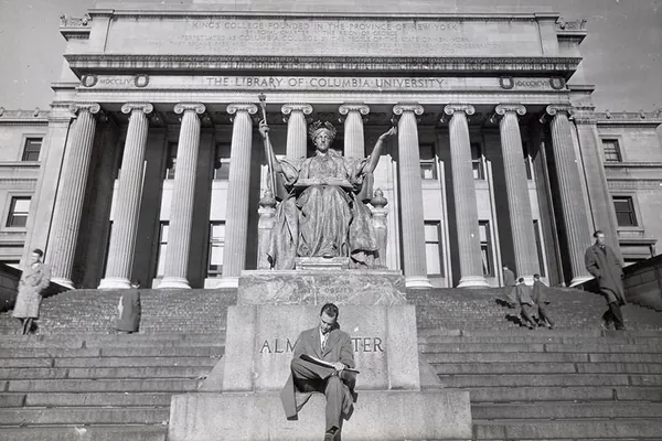 A student in the 1940s reads on the steps of Columbia’s Low Library, at the base of the Alma Mater statue
