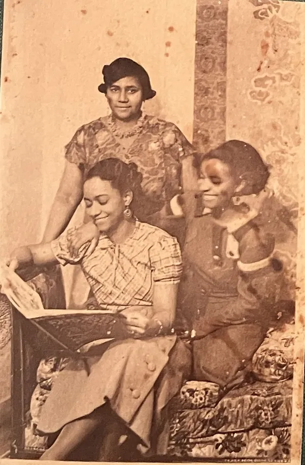 Lucy, Paulette and Jeanne Nardal looking at a book together in their apartment in Clamart