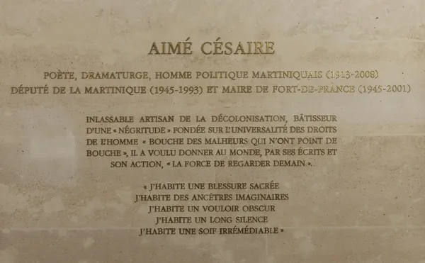 Gilded capitals on a stone wall: “Aimé Césaire, poète, dramaturge, homme politique martiniquais (1913–2008)”, with a tribute and lines from his poetry beginning “J’habite une blessure sacrée”